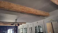 Grille discrète de climatisation gainable intégrée dans une pièce avec poutres apparentes à Salon-de-Provence