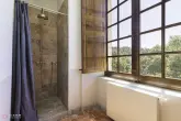 Salle de bain, douche avec caniveau et radiateur murale.
